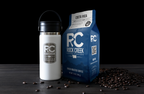 Rock Creek Coffee Roasters Costa Rica Santa Elena medium roast whole bean coffee in a blue 12 oz bag displayed beside a white insulated travel mug, with roasted coffee beans scattered on a dark tabletop.