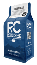 Rock Creek Coffee Roasters Colombian Santa Maria medium roast whole bean coffee in a 12 oz blue bag, featuring tasting notes of fruity, chocolate, caramel, and toffee, isolated on a white background.