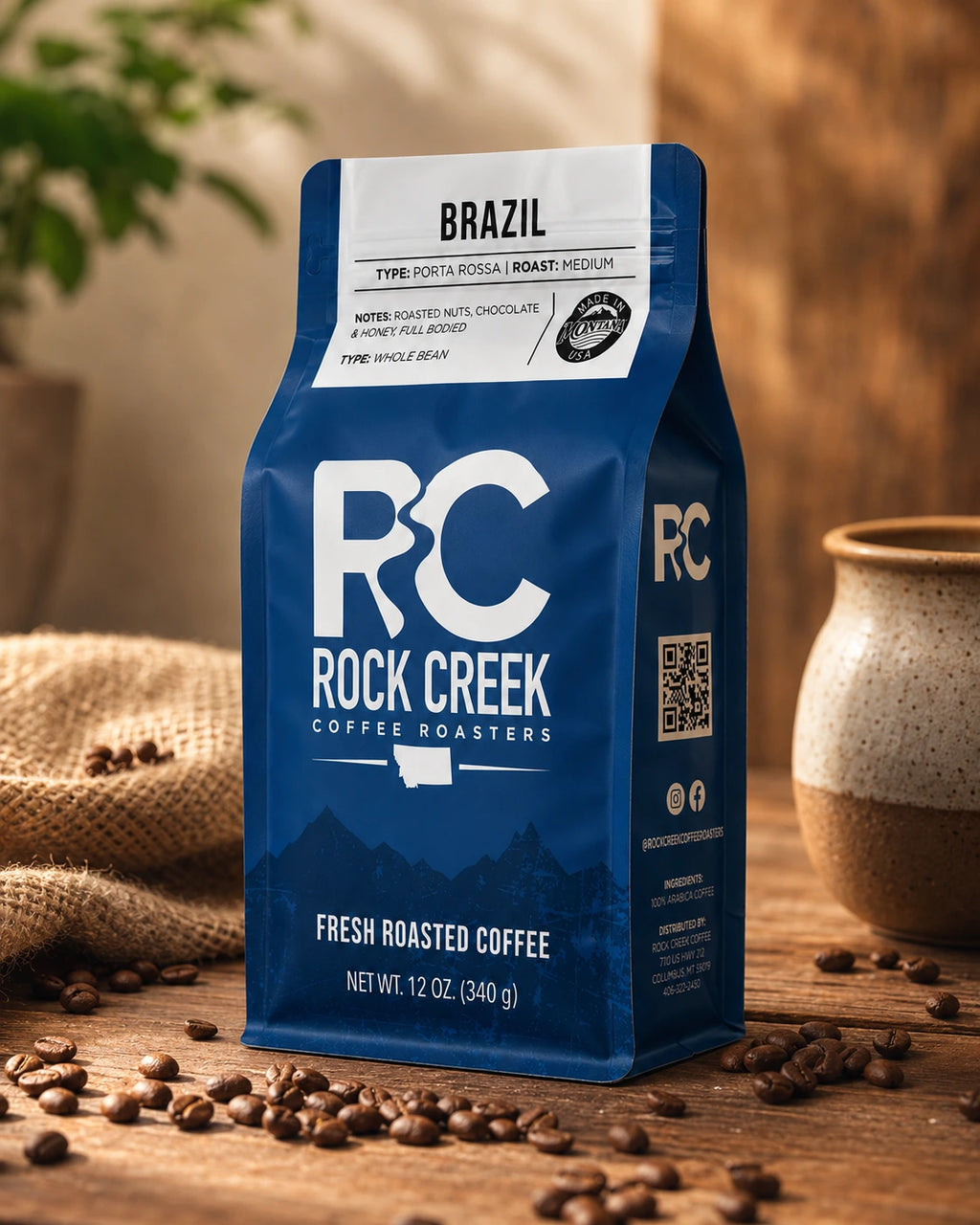 Rock Creek Coffee Roasters Brazil coffee bag in a warm craft coffee scene with roasted beans, burlap texture, and rustic tabletop styling.