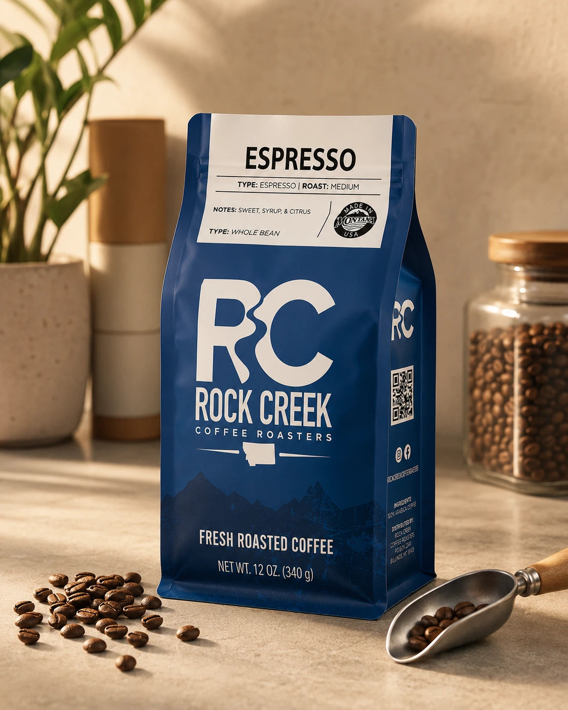 Rock Creek Coffee Roasters Espresso coffee bag in a warm craft coffee scene with roasted beans, a coffee scoop, and soft natural lighting.
