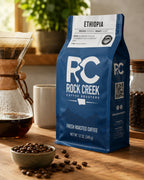 Rock Creek Coffee Roasters Ethiopia coffee bag near a pour-over brewing setup, roasted beans, and warm natural light.