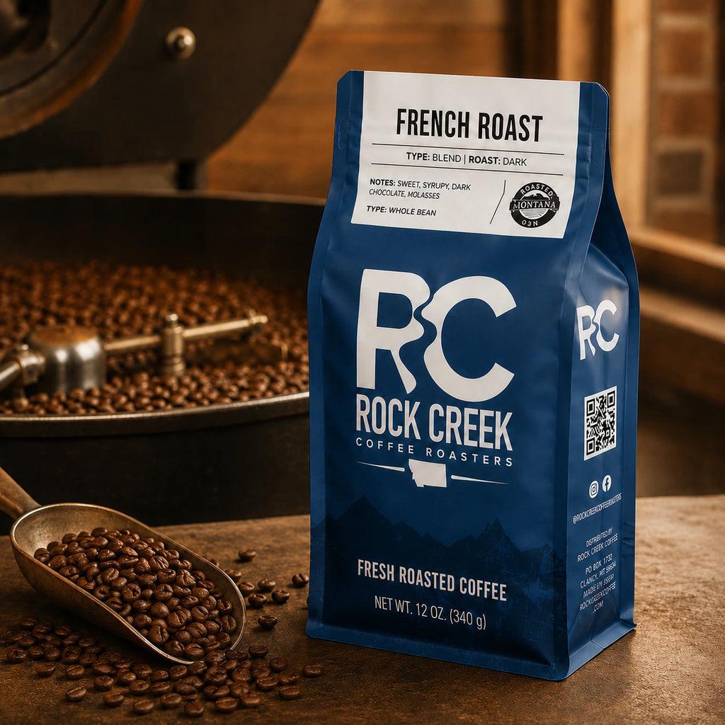 Rock Creek Coffee Roasters French Roast whole bean coffee bag on a roastery worktable with roasted beans and a scoop.