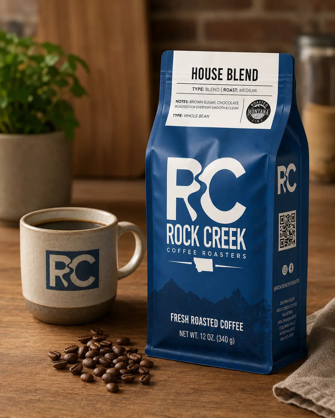 Rock Creek Coffee Roasters House Blend coffee bag on a warm wooden tabletop beside a ceramic mug of brewed coffee and scattered roasted coffee beans.