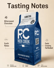 Load image into Gallery viewer, Rock Creek Coffee Roasters Sumatra dark roast coffee bag centered on a warm beige tasting notes graphic, with callouts for bittersweet chocolate, earth notes, and a creamy full-bodied profile, plus product details for Mandheling region, dark roast, and whole bean coffee.