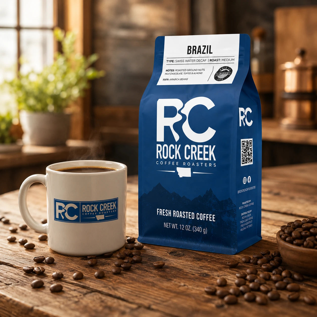 Rock Creek Coffee Roasters Brazil coffee bag on a rustic wooden table beside a branded coffee mug, brewed coffee, and scattered roasted coffee beans.