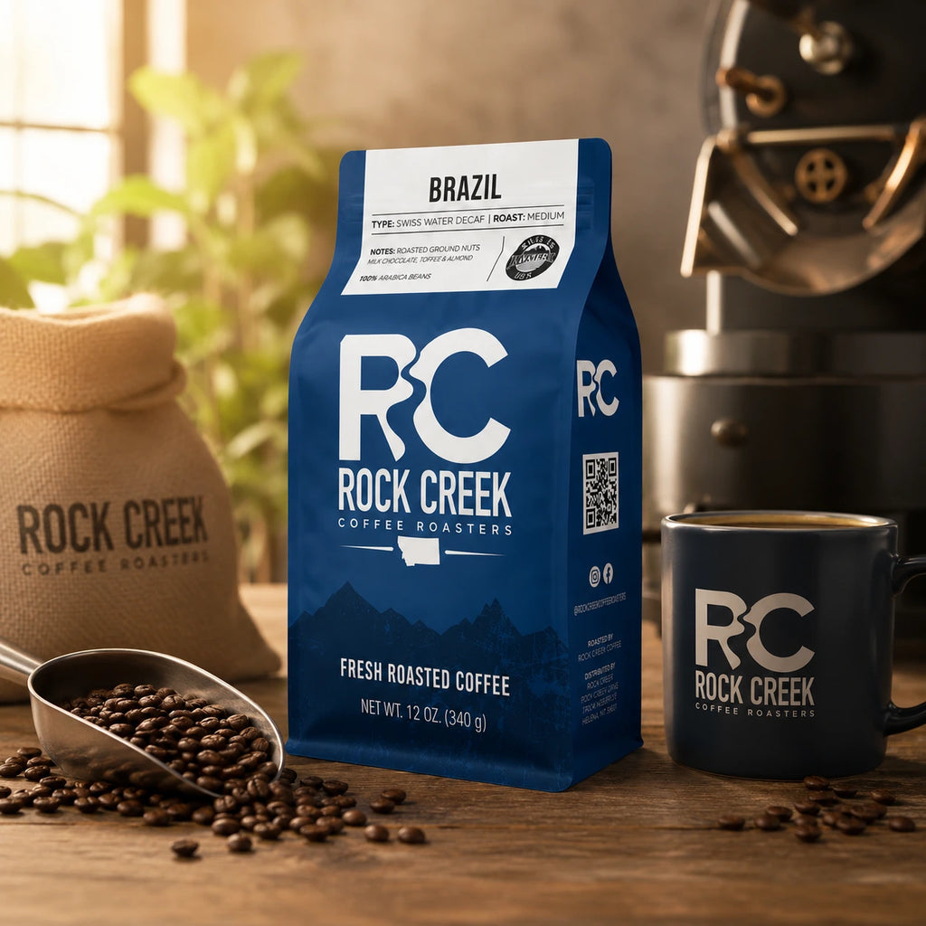 Rock Creek Coffee Roasters Brazil coffee bag in a warm roastery-inspired scene with coffee beans, a scoop, branded mug, burlap coffee sack, and soft natural light.