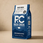 Rock Creek Coffee Roasters Wush Wush coffee bag standing upright on a warm neutral studio background.