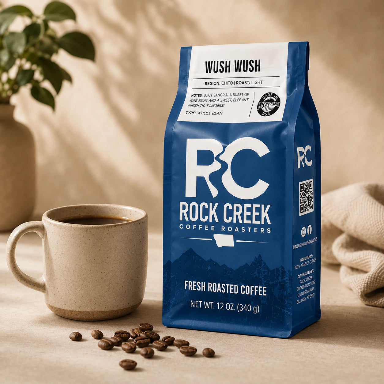 Rock Creek Coffee Roasters Wush Wush coffee bag beside a mug of brewed coffee and scattered roasted beans in warm natural light.