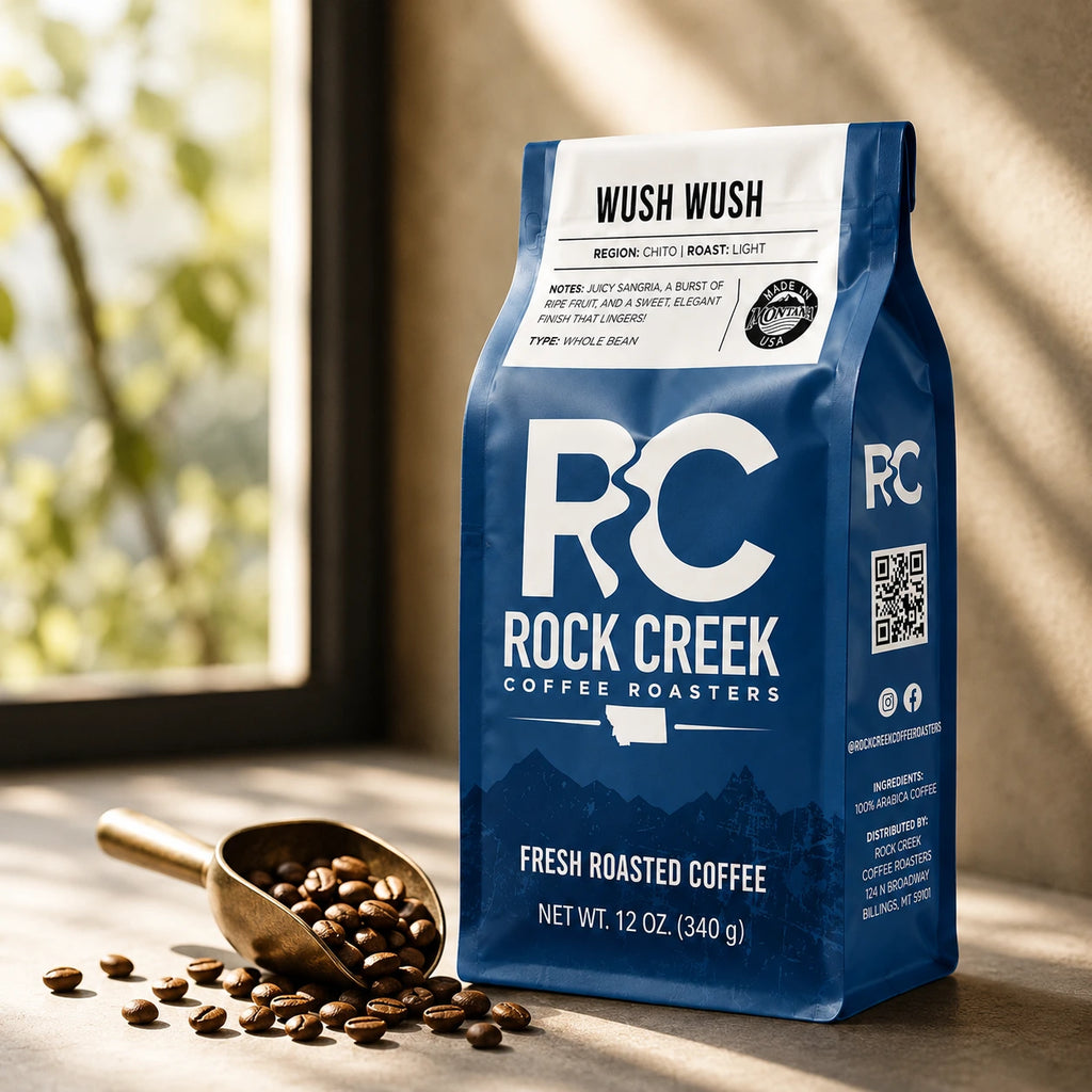 Rock Creek Coffee Roasters Wush Wush coffee bag near a scoop of roasted beans in warm roastery-style window light.