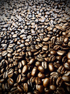 Close-up view of freshly roasted whole coffee beans filling the frame, showing rich brown tones and glossy surfaces.